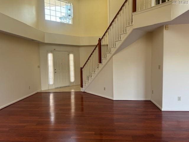 entrance foyer featuring baseboards, wood finished floors, a high ceiling, and stairs