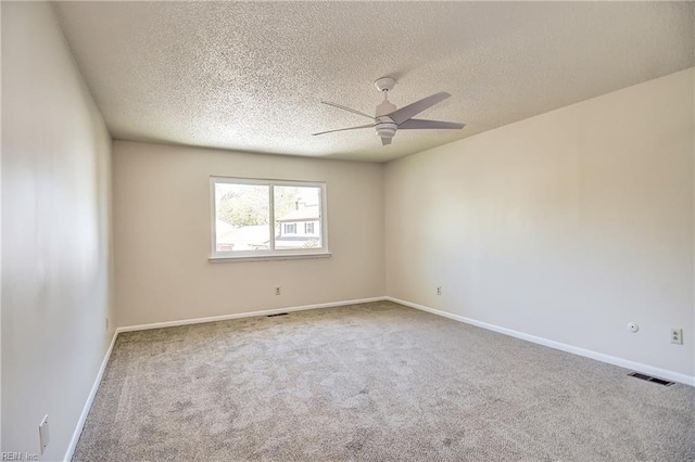 empty room featuring a ceiling fan, a textured ceiling, visible vents, and carpet