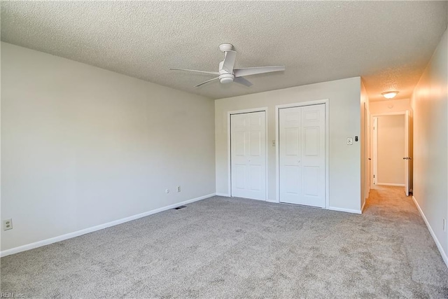 unfurnished bedroom with multiple closets, carpet floors, a textured ceiling, and baseboards