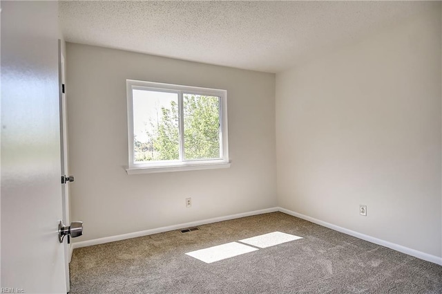 empty room with baseboards, visible vents, carpet floors, and a textured ceiling