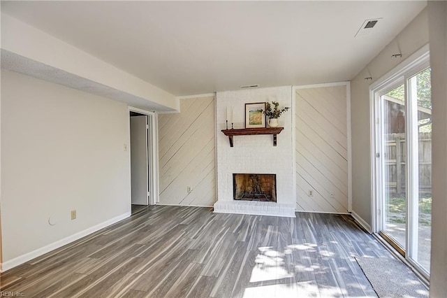 unfurnished living room featuring baseboards, wood finished floors, visible vents, and a fireplace