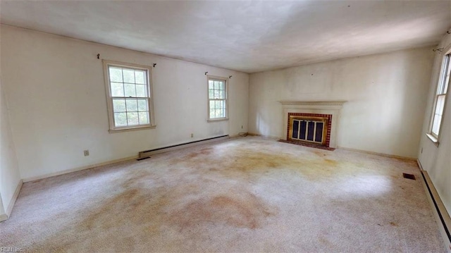 unfurnished living room featuring carpet floors, baseboard heating, a brick fireplace, and a wealth of natural light