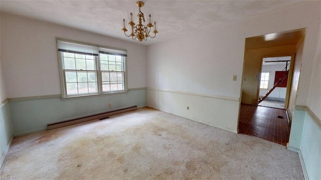 empty room with baseboards, an inviting chandelier, baseboard heating, and carpet