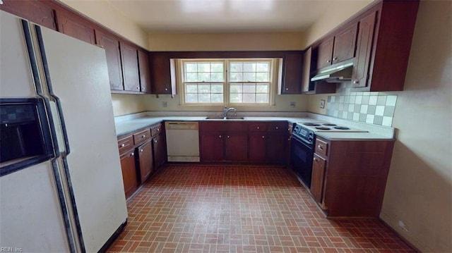 kitchen with brick patterned floor, white appliances, light countertops, under cabinet range hood, and tasteful backsplash