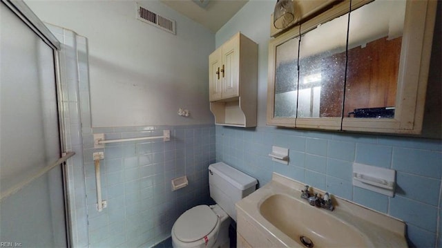 bathroom with visible vents, tile walls, toilet, and a shower stall