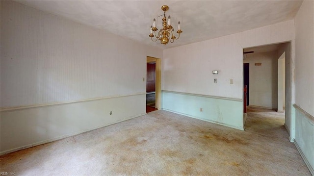 spare room featuring carpet floors and an inviting chandelier