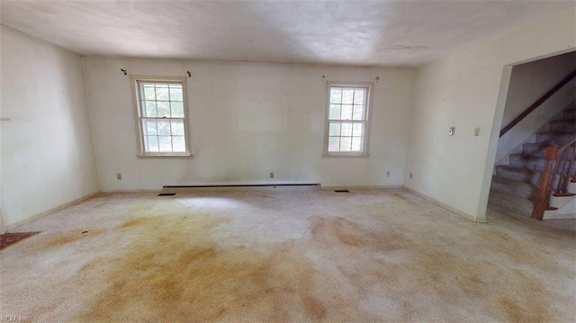 carpeted empty room featuring a baseboard radiator, baseboards, plenty of natural light, and stairs
