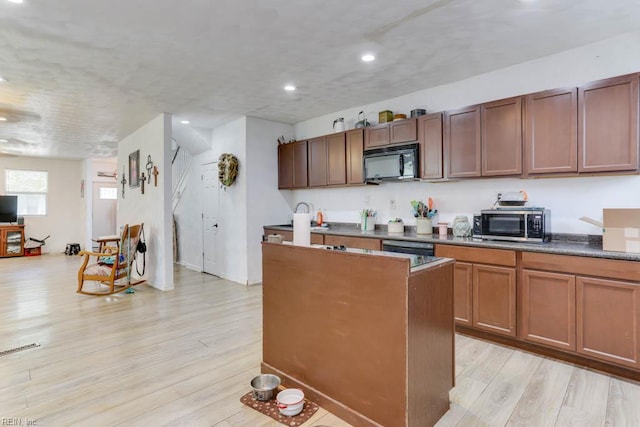 kitchen featuring recessed lighting, light wood-style flooring, stainless steel microwave, a kitchen island, and black microwave