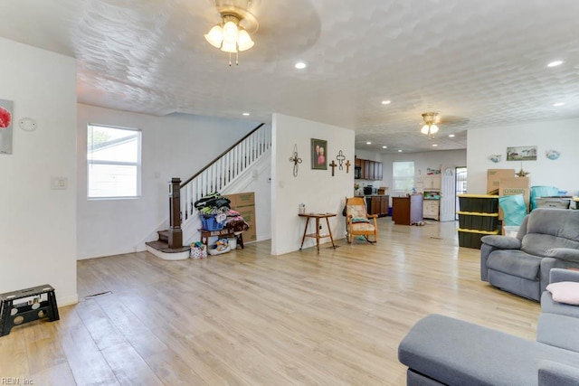 living room with light wood finished floors, stairs, ceiling fan, and recessed lighting