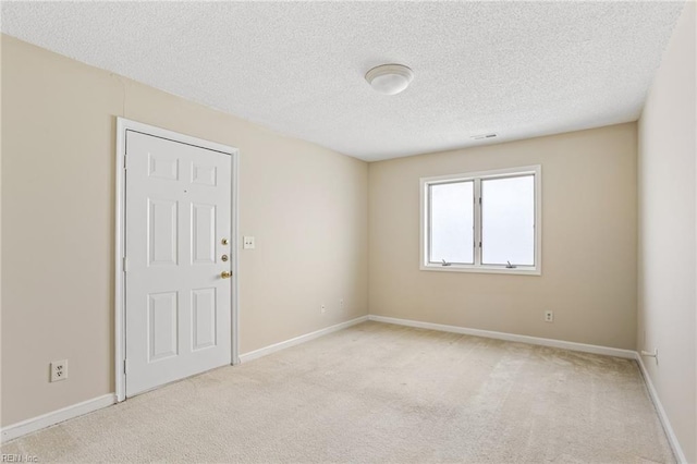 unfurnished room with baseboards, a textured ceiling, and light colored carpet