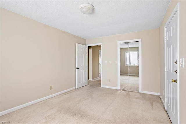 unfurnished bedroom with light carpet, baseboards, a textured ceiling, and a closet