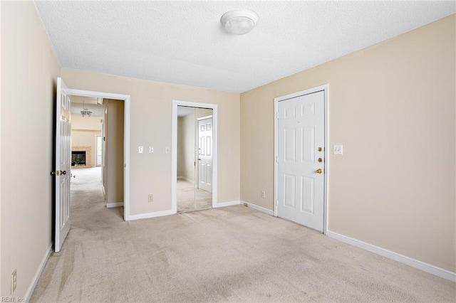 interior space featuring light colored carpet, baseboards, and a textured ceiling