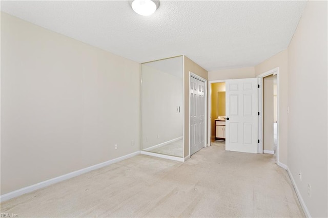 empty room with a textured ceiling, baseboards, and light carpet
