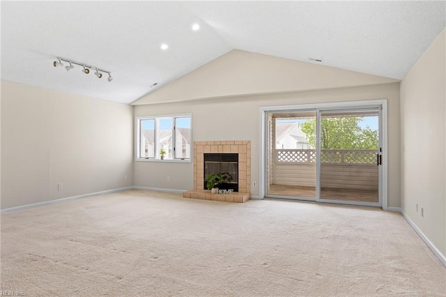 unfurnished living room featuring a tile fireplace, vaulted ceiling, visible vents, carpet floors, and baseboards