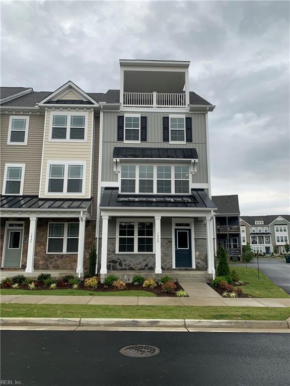 townhome / multi-family property featuring a standing seam roof, board and batten siding, and stone siding