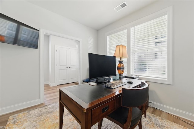 office area featuring baseboards, visible vents, and light wood-type flooring