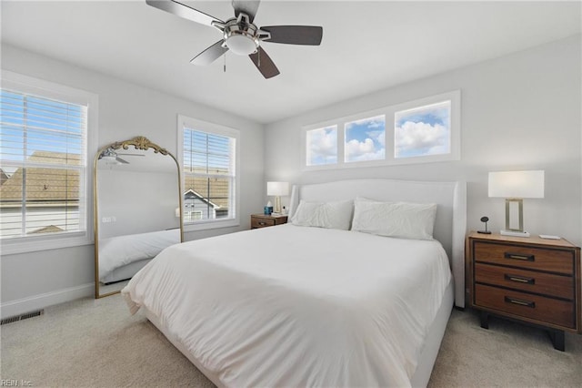 bedroom with light colored carpet, visible vents, a ceiling fan, and baseboards