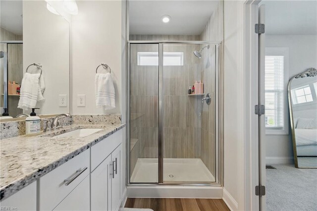 ensuite bathroom featuring a stall shower, vanity, and plenty of natural light