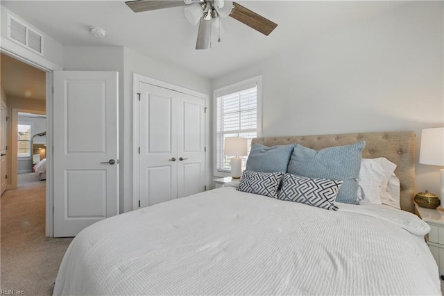 bedroom with visible vents, a ceiling fan, a closet, and carpet