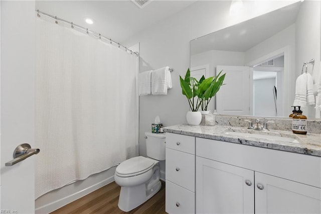 bathroom featuring wood finished floors, shower / bath combination with curtain, toilet, and vanity