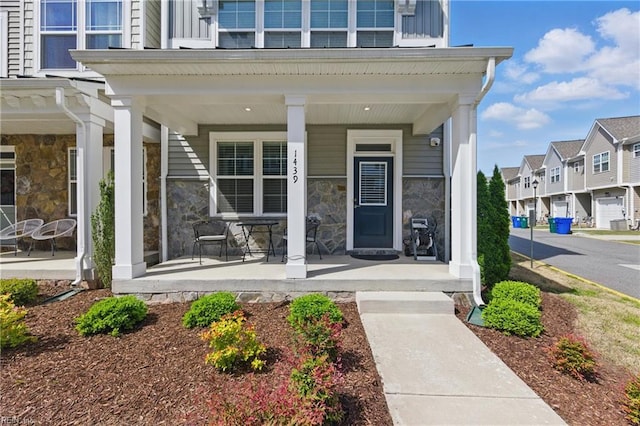 property entrance with a residential view, stone siding, and covered porch