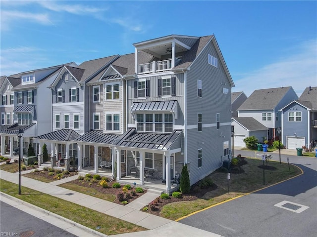 townhome / multi-family property featuring a standing seam roof, a balcony, a residential view, ceiling fan, and covered porch