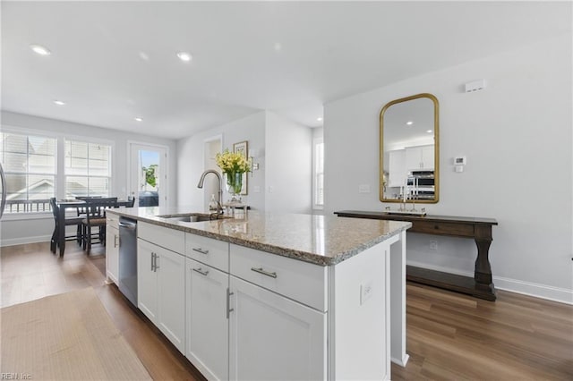 kitchen with dark wood-style floors, recessed lighting, light stone counters, and a sink