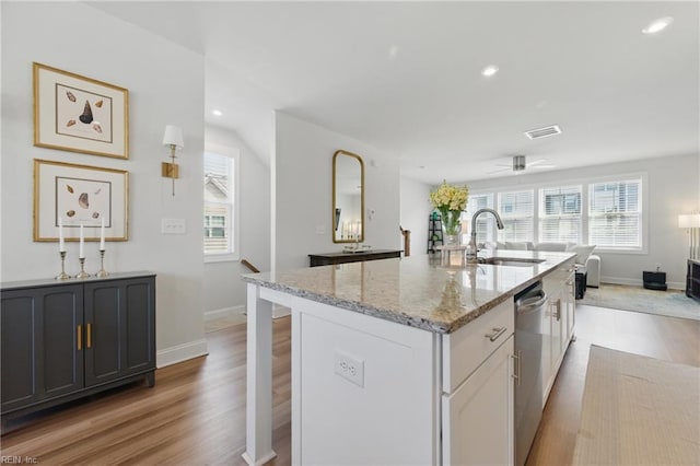 kitchen featuring visible vents, light stone counters, plenty of natural light, and a sink