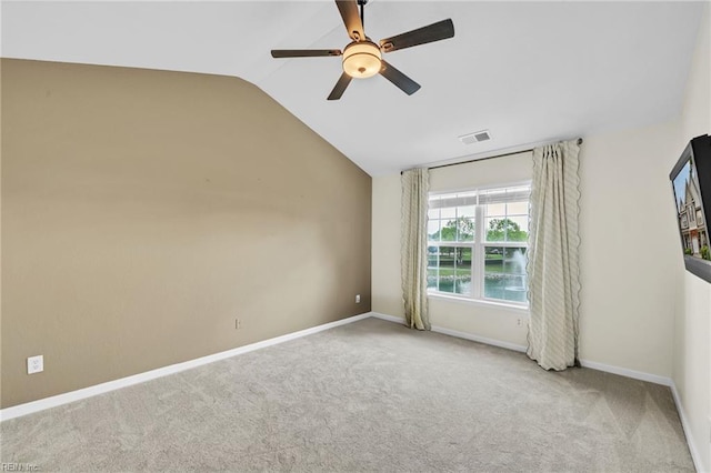 carpeted spare room featuring vaulted ceiling, visible vents, baseboards, and ceiling fan