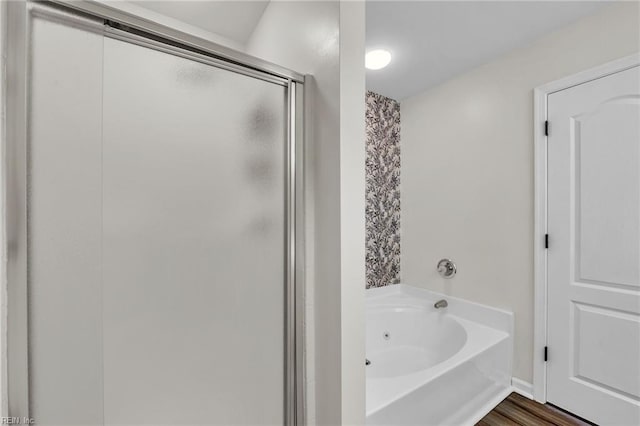 bathroom with a garden tub, wood finished floors, and a stall shower