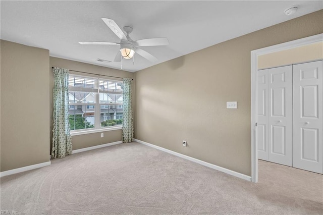 unfurnished room with carpet floors, visible vents, baseboards, and ceiling fan