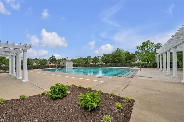 community pool with a pergola, an outbuilding, a patio area, and a shed