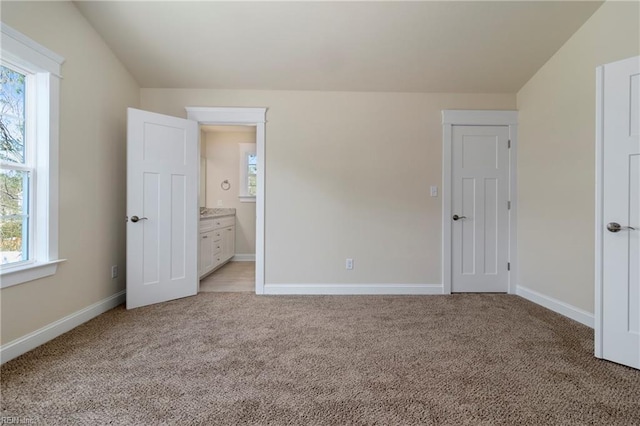 unfurnished bedroom featuring baseboards, light carpet, and connected bathroom