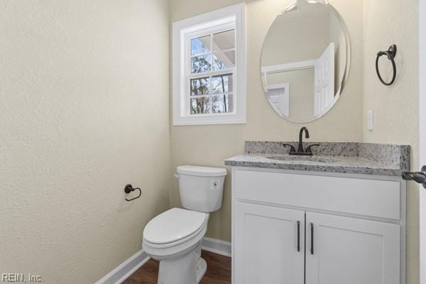 bathroom featuring baseboards, toilet, vanity, and wood finished floors