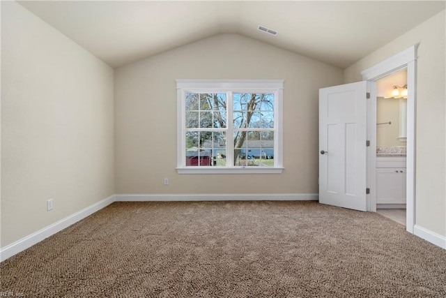 unfurnished bedroom featuring lofted ceiling, baseboards, visible vents, and carpet