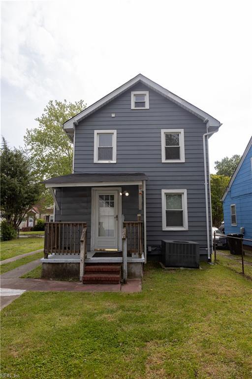 rear view of house with fence, a lawn, and central AC unit