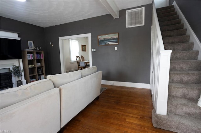 living area featuring stairway, wood finished floors, visible vents, baseboards, and a fireplace
