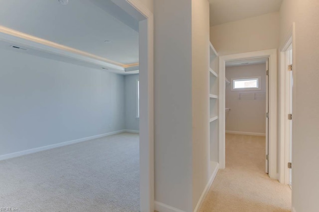 hall featuring light colored carpet and baseboards