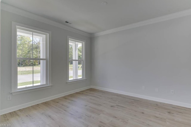 spare room with wood finished floors, visible vents, baseboards, and ornamental molding