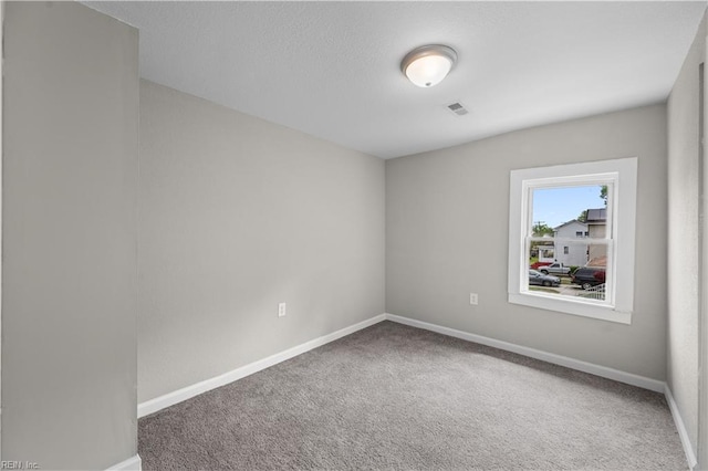carpeted spare room featuring a textured ceiling, visible vents, and baseboards