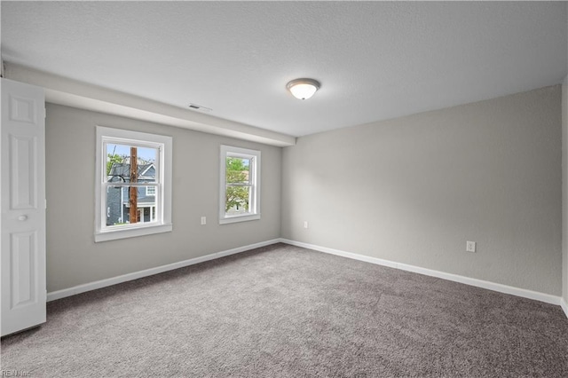 empty room with visible vents, baseboards, carpet flooring, and a textured ceiling