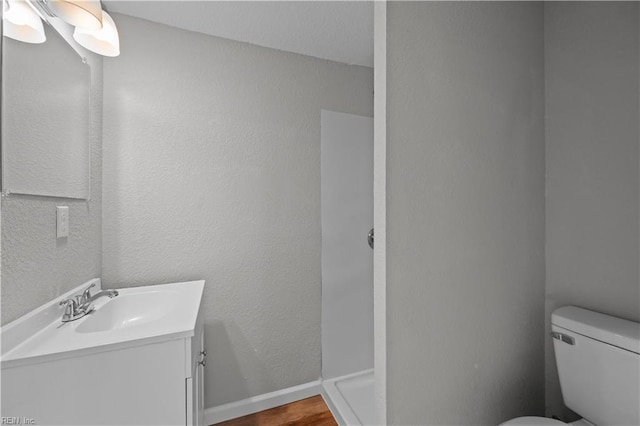 bathroom featuring toilet, vanity, and wood finished floors