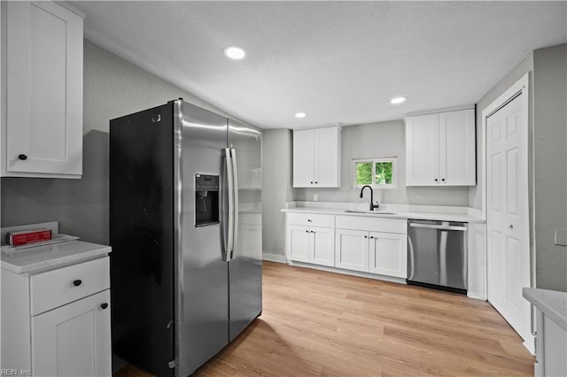 kitchen with white cabinets, stainless steel appliances, a sink, recessed lighting, and light countertops