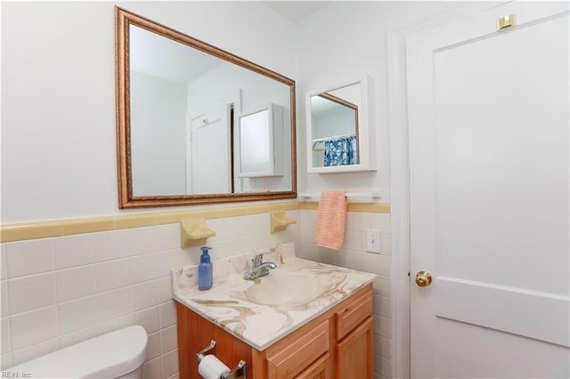 bathroom featuring tile walls, a wainscoted wall, vanity, and toilet