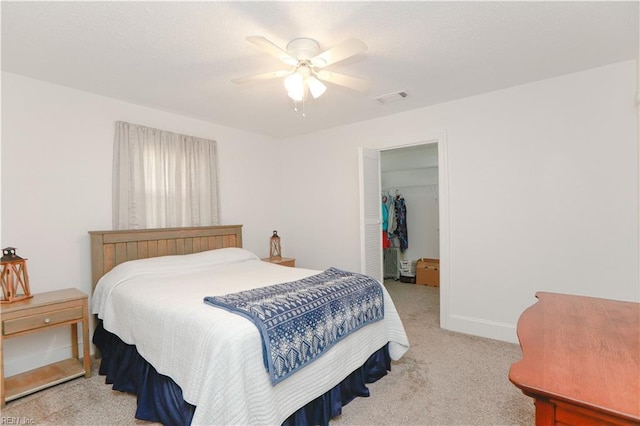 bedroom with a spacious closet, visible vents, a ceiling fan, a closet, and light colored carpet