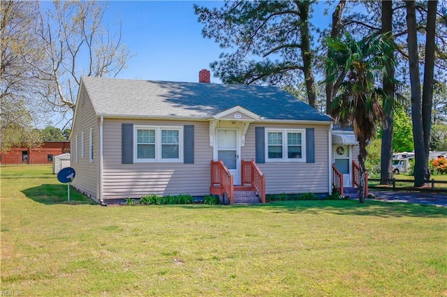 bungalow-style home featuring entry steps, a chimney, and a front yard