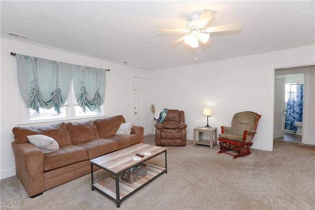 living area featuring a textured ceiling, carpet floors, visible vents, and ceiling fan