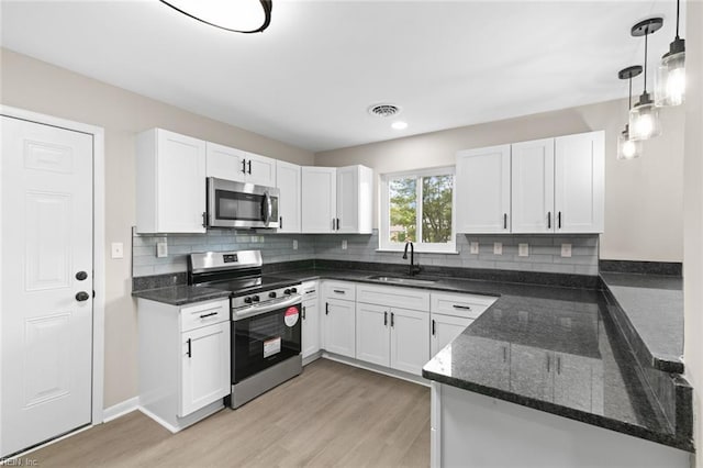 kitchen with white cabinetry, stainless steel appliances, light wood finished floors, and a sink