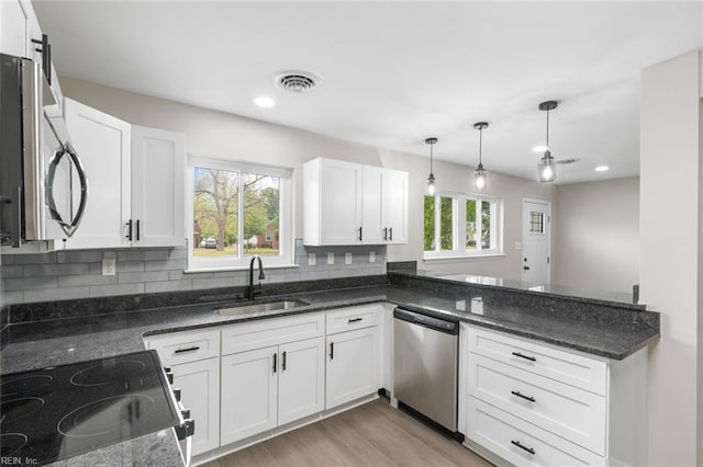 kitchen with white cabinets, a sink, visible vents, decorative backsplash, and appliances with stainless steel finishes