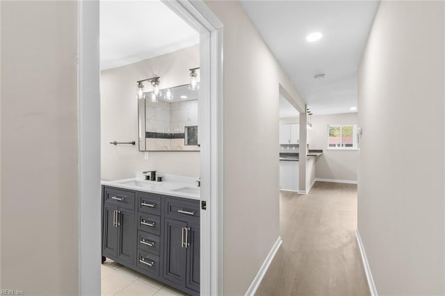 hallway featuring baseboards and a sink